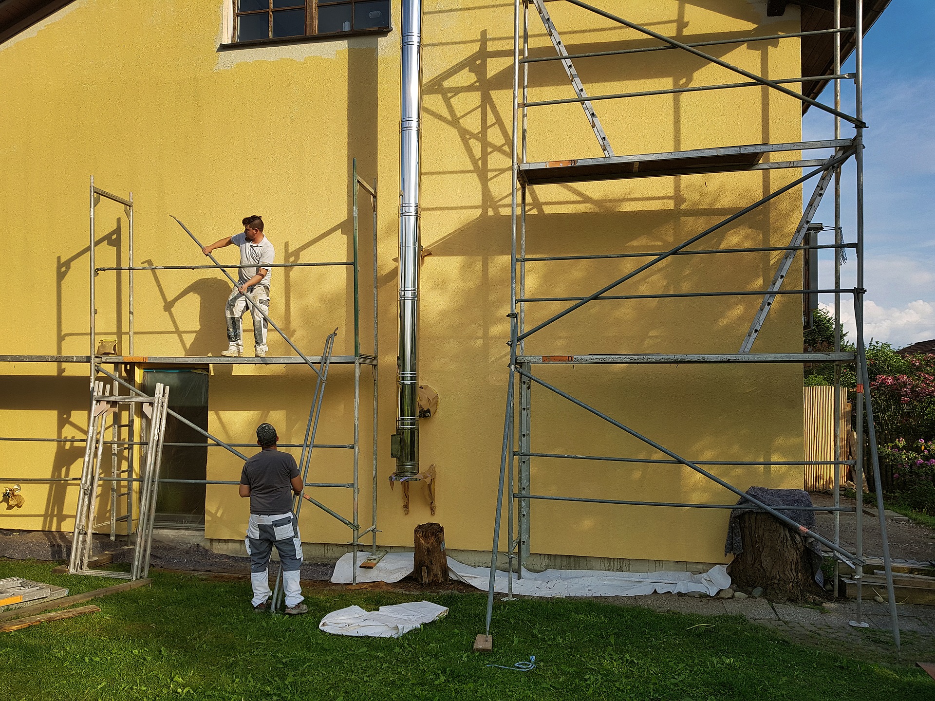 scaffold two men painting exterior wall, one on scaffold